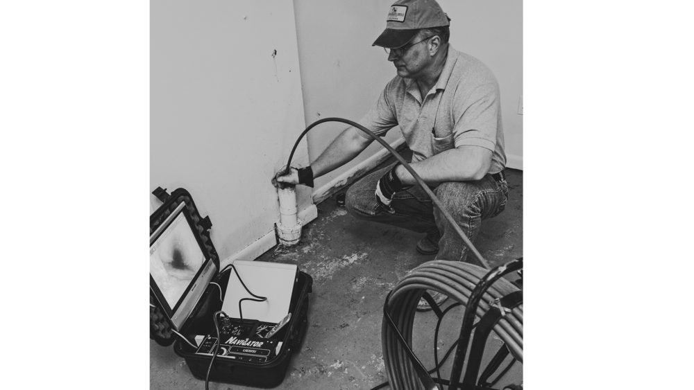 Frank Taciak performing a video camera pipe inspection inside a basement cleanout