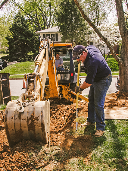 backhoe grading dirt and backfilling trench from sewer repair